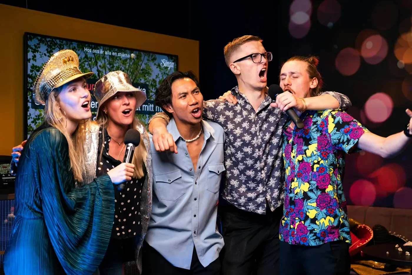 Groep collega's zingt samen met microfoons tijdens de Knallende Karaoke