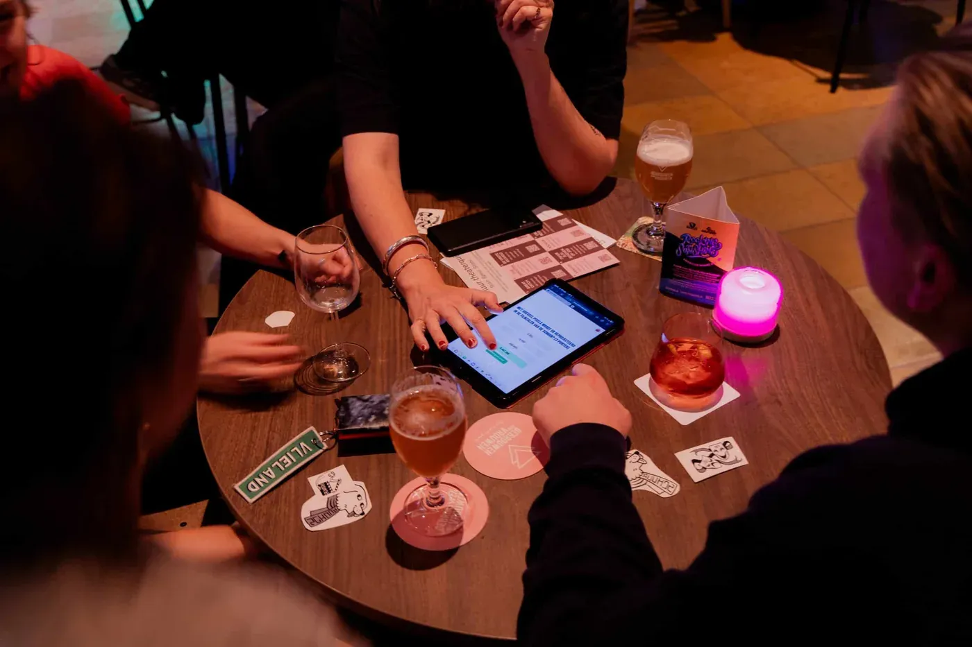 Team speelt de Knal & Co. pubquiz op een tablet aan een cafétafel